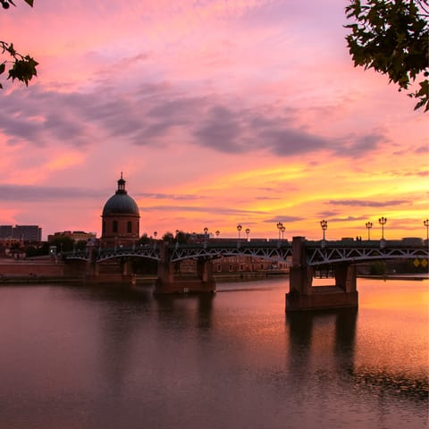 Amble along the banks of the Garonne River and admire the sun setting over Pont Neuf
