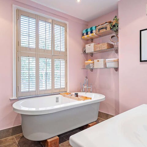 Allow the soft pink of the bathroom to relax you as you bathe in this freestanding tub
