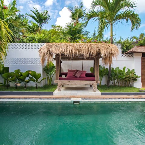 Relax on the antique Balinese daybed by the private pool
