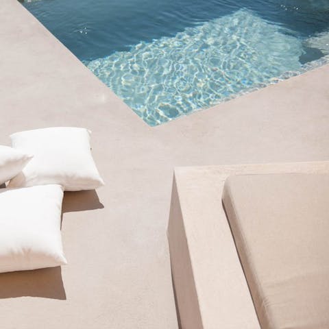 Stretch out by the pool beneath cloudless Santorini skies