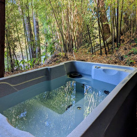 Unwind in the private hot tub, set against the stunning natural scenery 