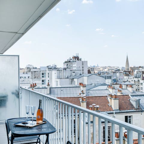 Sip wine on the balcony as the sun sets over Paris