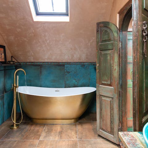 Enjoy a rejuvenating soak in the elegant gold free-standing bathtub
