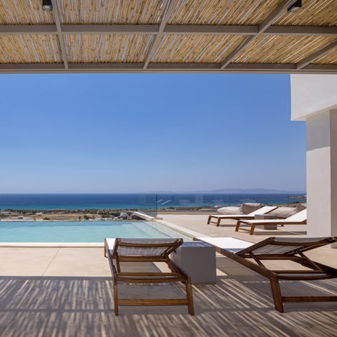 Lounge by the poolside and admire the crystal clear Aegean Sea